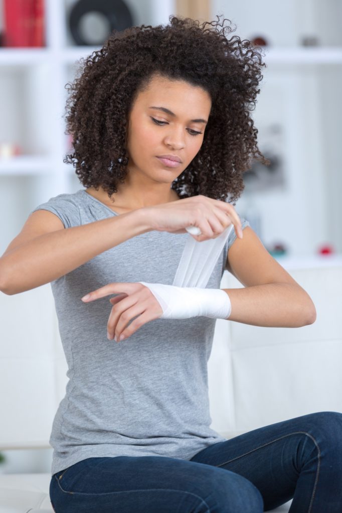 woman bandaging her wrist indoors